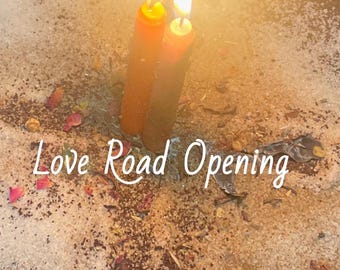 Peut inclure: Deux bougies orange allumées sont dressées dans un lit de poudre granulaire claire, de pétales de fleurs séchées et d'herbes éparpillées. Le texte Love Road Opening est écrit en lettres blanches au centre, illuminé par les flammes des bougies.