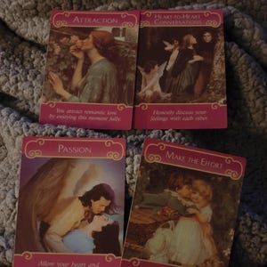 May include: Four rectangular oracle cards with pink borders and romantic illustrations. The cards are titled Attraction, Heart-to-Heart Conversations, Passion, and Make the Effort, each featuring printed text messages at the bottom of the cards.