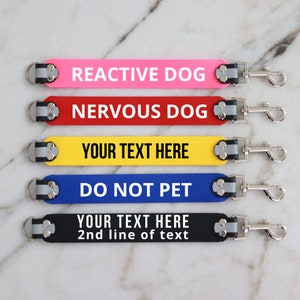 以下が含まれることがあります： 金属製のクリップが付いた、5色の異なる犬用リードタグ。タグはピンク、赤、黄色、青、黒です。タグのテキストは、「Reactive Dog」、「Nervous Dog」、「Your Text Here」、「Do Not Pet」、「Your Text Here 2nd line of text」です。