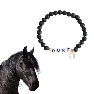 May include: Black lava rock bracelet with gold beads and white letter beads spelling "DUKE" and a gold horseshoe charm.