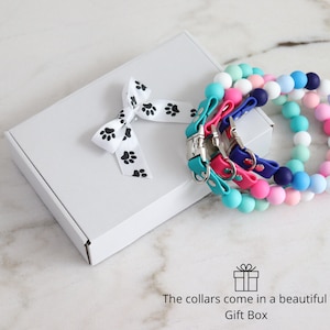 May include: Three colorful dog collars with silver buckles come in a white gift box with a black paw print ribbon. The collars come in a beautiful gift box.