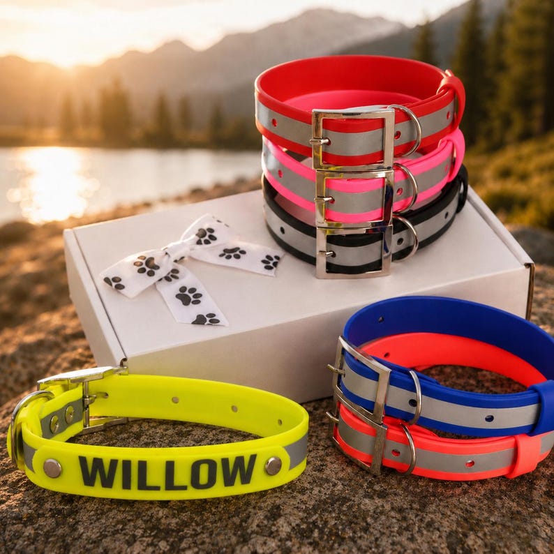 May include: A collection of waterproof dog collars in red, pink, black, blue, orange, and neon yellow, featuring silver metal buckles and reflective strips. One yellow collar displays the name WILLOW in black letters. A white bow with paw prints is included.