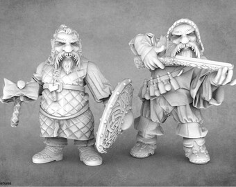 Puede incluir: Dos figuras en miniatura de enanos, uno sosteniendo un martillo y un escudo, el otro sosteniendo una espada. Ambos llevan una armadura de malla y tienen largas barbas.