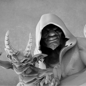 Puede incluir: Una figura gris con capucha y una expresión amenazante sostiene un pequeño demonio alado con cuernos. La figura sostiene un bastón con un diseño en forma de cráneo.