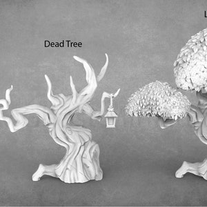 Op de afbeelding: Drie 3D-geprinte miniatuur bomen, een grote, een dode en een kleine, met een lantaarnpaal. Elke boom heeft een lantaarn die aan een tak hangt.