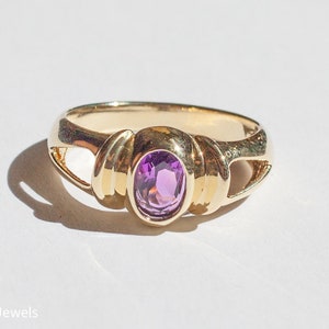 May include: A gold ring with a purple oval gemstone set in a twisted band.