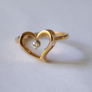 May include: A gold heart-shaped ring with a small diamond in the center.
