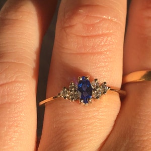 May include: A gold ring with a blue oval sapphire and smaller diamonds set around it.