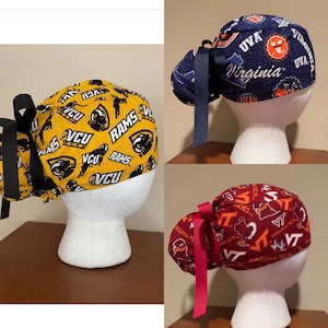 May include: Three scrub caps on mannequin heads. One is gold with black VCU Rams logos, another is navy blue with UVA and Virginia text, and the third is maroon with VT and Virginia Tech text.