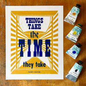 Puede incluir: Una impresión con la cita "THINGS TAKE the TIME they take" en azul y amarillo. La imagen incluye cuatro tubos de tintas Caligo Safe Wash Relief: ocre amarillo, amarillo arilida, azul ftalo y diluyente, cada uno de 75 ml.