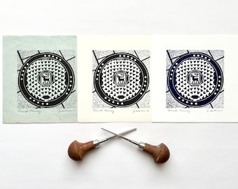 Tapa de alcantarilla de reno de Tromso, Noruega, 6 x 6, impresión en relieve de linograbado, obra de arte de pared original hecha a mano de 6 x 6, regalo de explorador viajero con escudo de armas
