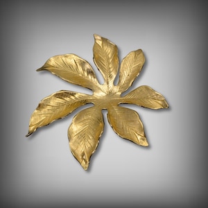 May include: A gold-colored metal leaf-shaped decorative tray with a textured surface.