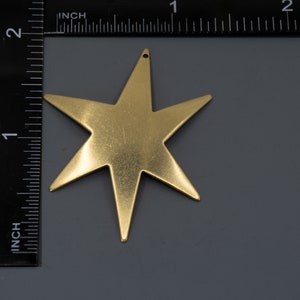 K&ouml;nnte beinhalten: Ein goldfarbener, f&uuml;nfzackiger sternf&ouml;rmiger Anh&auml;nger mit einem Loch oben.