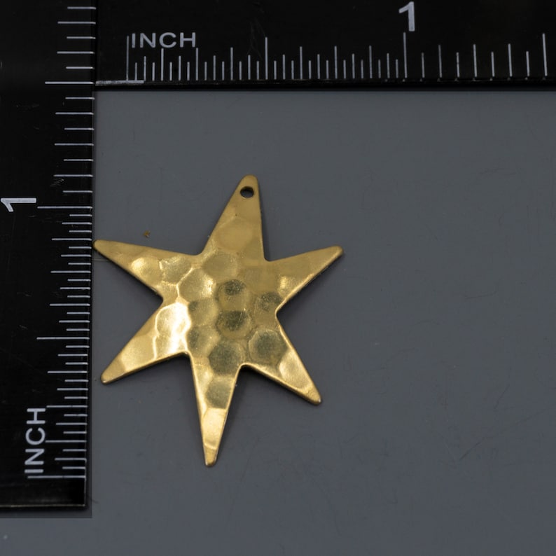 May include: A gold-colored, hammered metal star charm with a hole at the top for hanging.