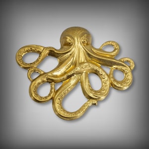May include: A gold-colored metal octopus with eight tentacles. The octopus is detailed with textured rings around each tentacle.