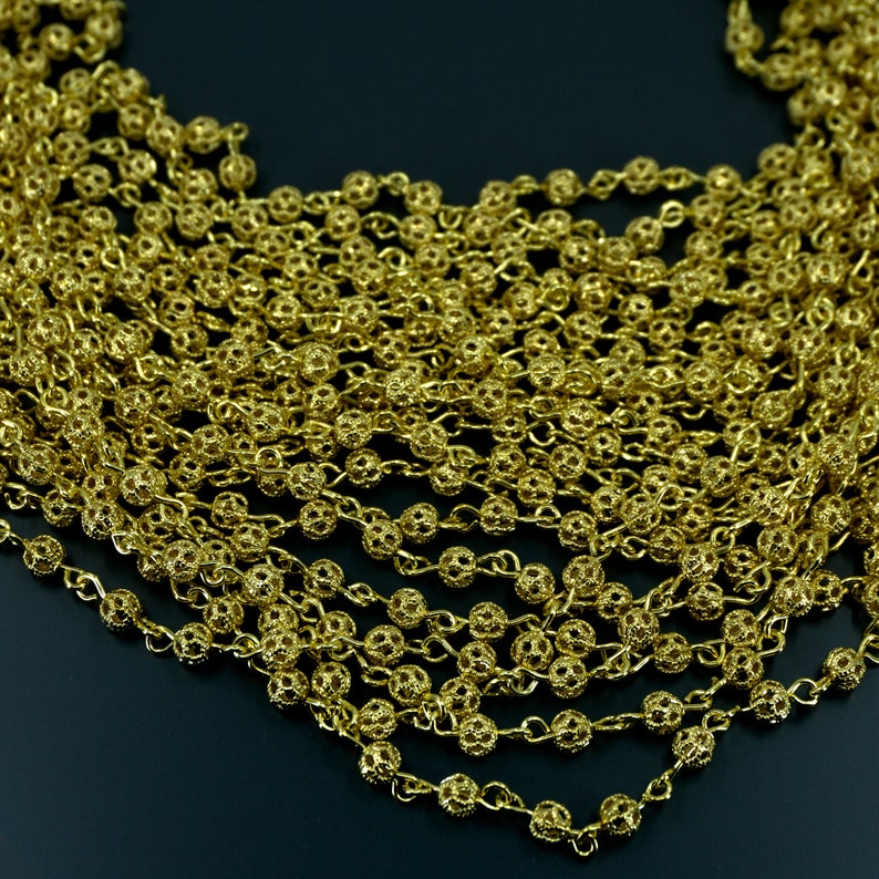 Puede incluir: Un collar de cadena dorada con peque&ntilde;os eslabones redondos e intrincados. La cadena est&aacute; hecha de metal y tiene un aspecto delicado y femenino.