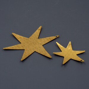 May include: Two gold-colored metal star shapes with a hammered texture. The larger star is about 5 inches wide and the smaller star is about 3 inches wide.
