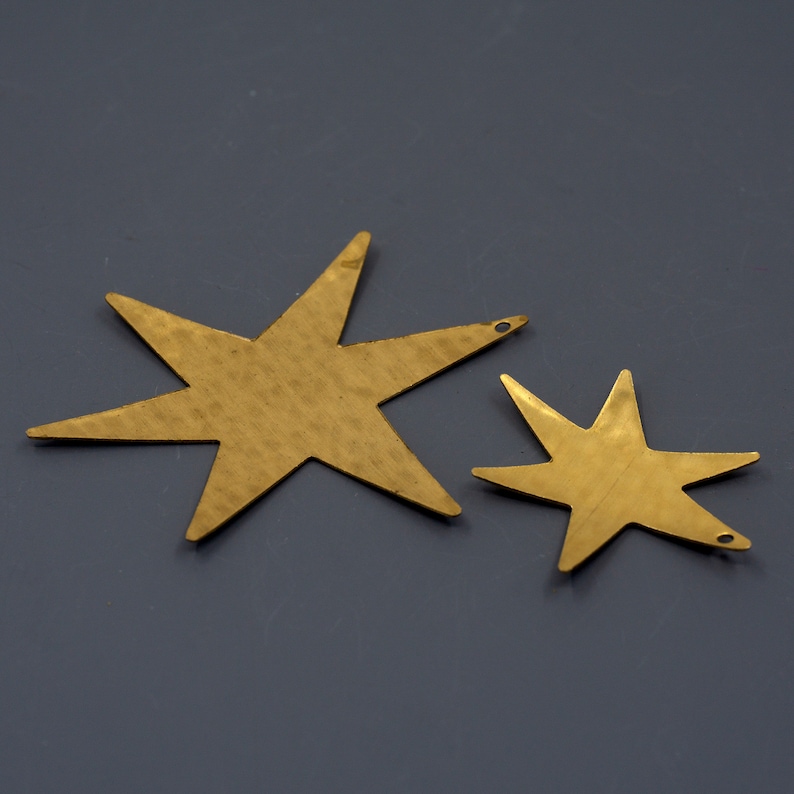 May include: Two gold-colored metal star shapes with a hammered texture. The larger star is about 5 inches wide and the smaller star is about 3 inches wide.