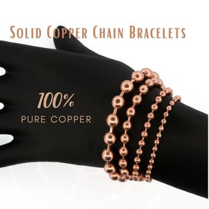 May include: Four solid copper chain bracelets with varying bead sizes, displayed on a black form. The text reads SOLID COPPER CHAIN BRACELETS and 100% PURE COPPER. The metallic copper beads are arranged in a row, showcasing different diameters.