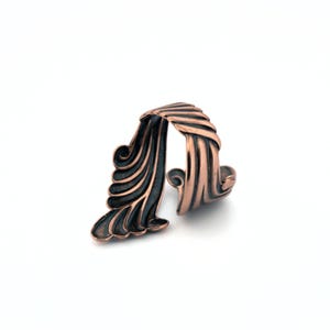 A copper-colored, twisted ring with a unique, swirling design.
