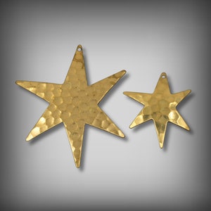 May include: Two gold-toned metal star-shaped ornaments with a hammered texture. The larger star is about 5 inches wide and the smaller star is about 3 inches wide.