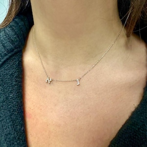 May include: A delicate gold chain necklace with two small diamond-encrusted letters, "N" and "J", hanging from it.