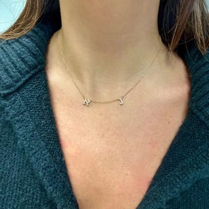 May include: A gold chain necklace with two small diamond-encrusted letters, "N" and "I", hanging from it.