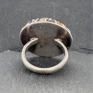 May include: Sterling silver ring with a multi-colored stone set in a bezel setting. The ring is marked "STERLING" and "MEXICO" on the back.