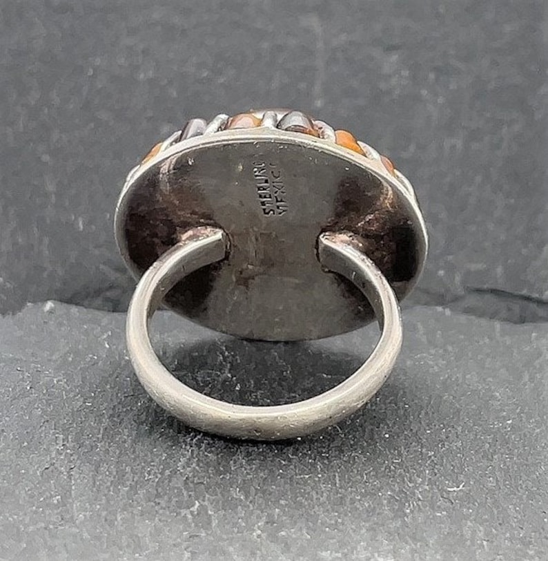 May include: Sterling silver ring with a multi-colored stone set in a bezel setting. The ring is marked "STERLING" and "MEXICO" on the back.