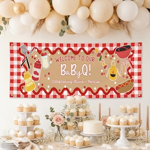 以下が含まれることがあります： 「Welcome to our BaBy Q!」の文字が赤とベージュで書かれたパーティーバナー。バーベキューをテーマにしたイラストが描かれています。バナーは赤と白のチェック柄の背景に配置されています。カップケーキ、ケーキ、風船があります。