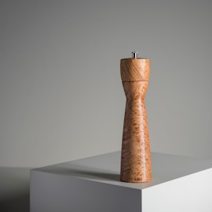 Op de afbeelding: Een houten pepermolen met een natuurlijke houtnerf afwerking. De molen is hoog en slank met een zilveren bovenkant. Het woord "Arbol" staat gedrukt op de onderkant van de molen.