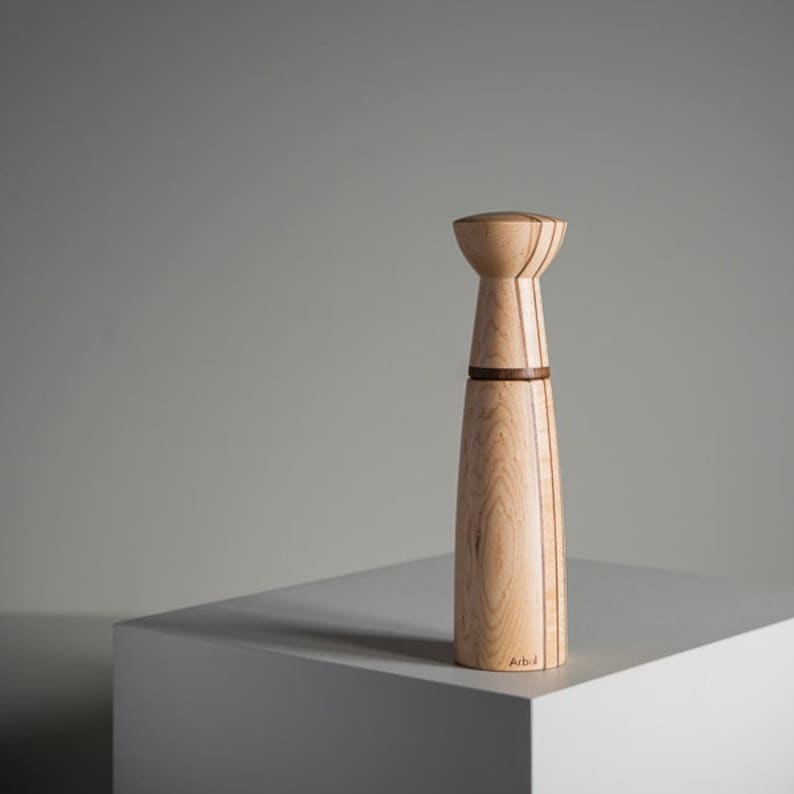 Op de afbeelding: Een houten zout- en pepermolen met een natuurlijke houten afwerking en bruine accenten. De molen is gemaakt van hout en heeft een cilindrische vorm. De molen is onderaan gelabeld met "Arb".
