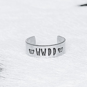 May include: Silver ring with the text "WWDD" and a butterfly on each side.