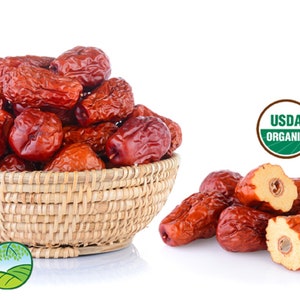 May include: A woven basket filled with dried, reddish-brown jujube fruits. Some jujubes are cut open, revealing the seed. The image includes USDA Organic and CCOF Organic certification logos, and the Wild Blue Organics logo.