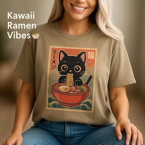 May include: A light brown t-shirt with a graphic of a black cat eating ramen noodles. The graphic is in a vintage style with Japanese text that says "Ramen" and "Cat".