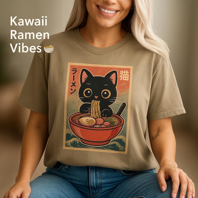 May include: A light brown t-shirt with a graphic of a black cat eating ramen noodles. The graphic is in a vintage style with Japanese text that says "Ramen" and "Cat".