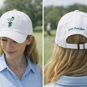May include: White baseball cap with a green embroidered cocktail glass design on the front. The back of the cap has the text "par then bar" in green. The cap has an adjustable strap.