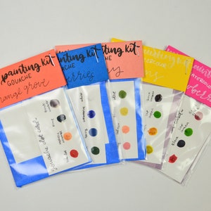 May include: Five mini painting kits with different color palettes. Each kit includes a small plastic bag with a card showing the colors and a label with the name of the kit. The kits are labeled "mini painting kit gouache orange grove", "mini painting kit gouache berries", "mini painting kit the sky", "mini painting kit watercolor lemons", and "mini painting kit watercolor berries".