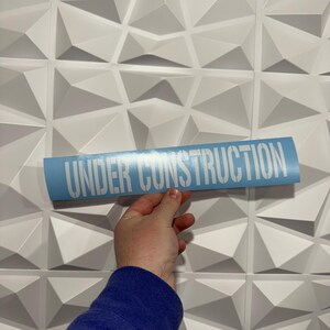 May include: A light blue sticker with the text "UNDER CONSTRUCTION" in white lettering.