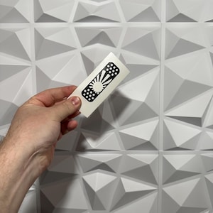 May include: A black and white vinyl sticker of a band-aid with a rising sun design.