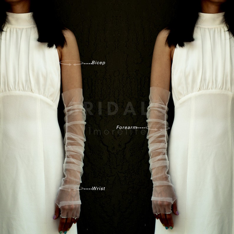 May include: A pair of white tulle elbow-length gloves with a gathered detail. The gloves are shown on a model wearing a white dress. The text "...Bicep", "...Forearm...", and "...Wrist" is visible on the image.