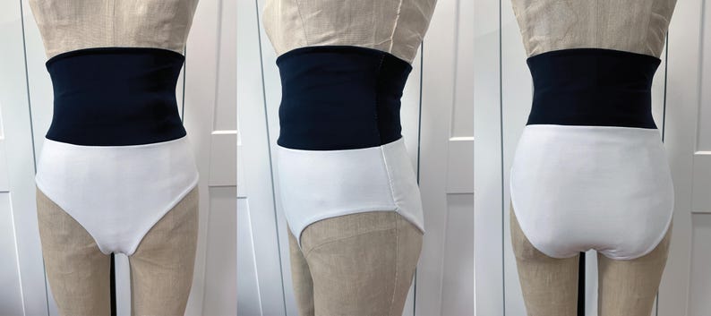 May include: A two-piece swimsuit with a high-waisted design. The top is a solid navy blue, and the bottoms are white. The swimsuit is displayed on a mannequin, showcasing the front, side, and back views of the garment.