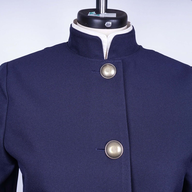 May include: A navy blue blazer with a mandarin collar and two silver buttons.