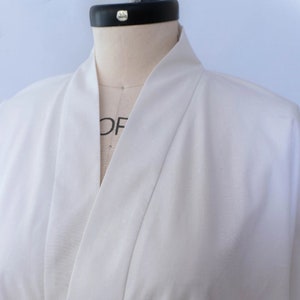 Puede incluir: Batista blanca con un cuello largo y puntiagudo. La bata est&aacute; hecha de una tela suave y ligera.