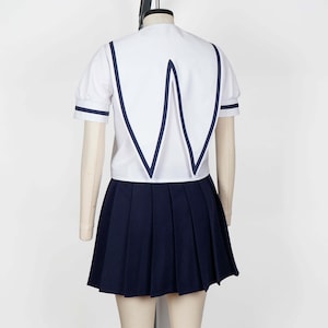 Full body shot of a mannequin wearing a white seifuku top with a navy blue jester collar and matching trim on the short sleeves. A dark navy blue skirt is visible beneath the top. The background is a plain white studio backdrop.