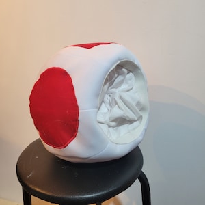 Photo of underview of the mushroom hat showing a full lining and an elastic that acts like a headband to keep the hat in place. Large red spots are sewn onto the sphere shaped hat.