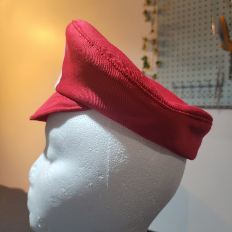 May include: A red and white hat with a brim. The hat is made of a soft fabric and has a simple design.