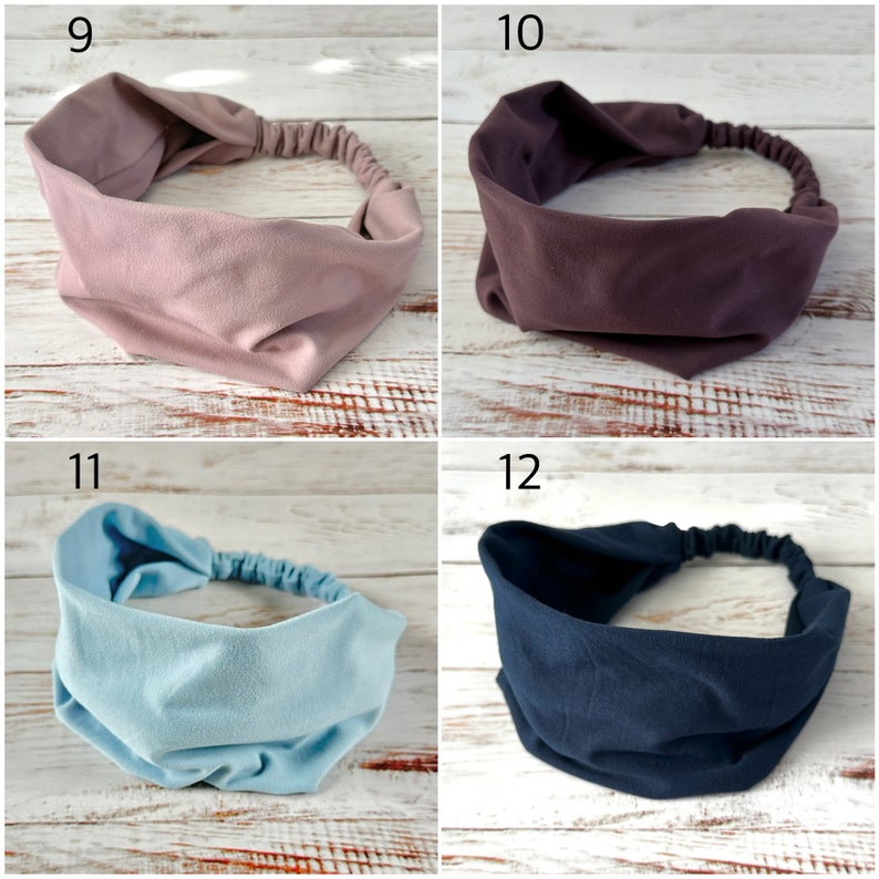 May include: A collection of four wide fabric headbands featuring a gathered elastic back for a secure fit. The set includes one dusty rose, one deep plum, one light sky blue, and one dark navy blue headband, each with a smooth, matte finish.