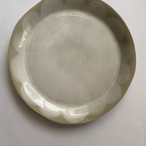 May include: A white ceramic plate with a scalloped edge. The plate has a subtle, textured surface.