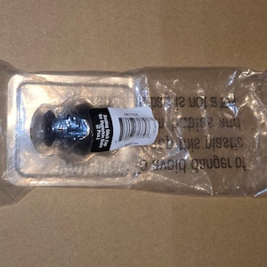 May include: A package containing two black analog stick caps for Hyperkin Duke. The caps are in a clear plastic package with a barcode label. The package is on a brown surface.